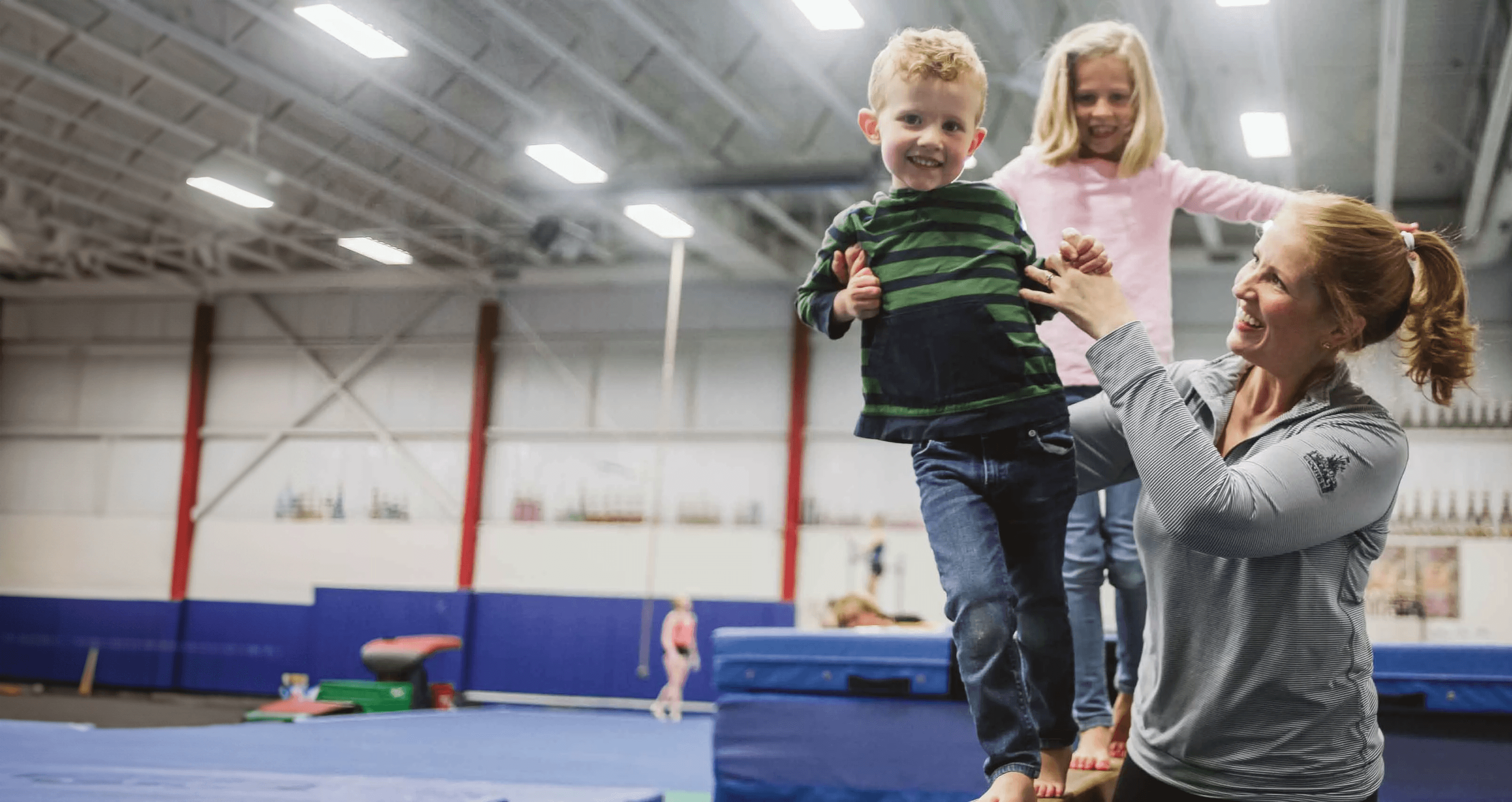 A coach assisting kids in balancing on a Gymnastic platform at a YMCA.