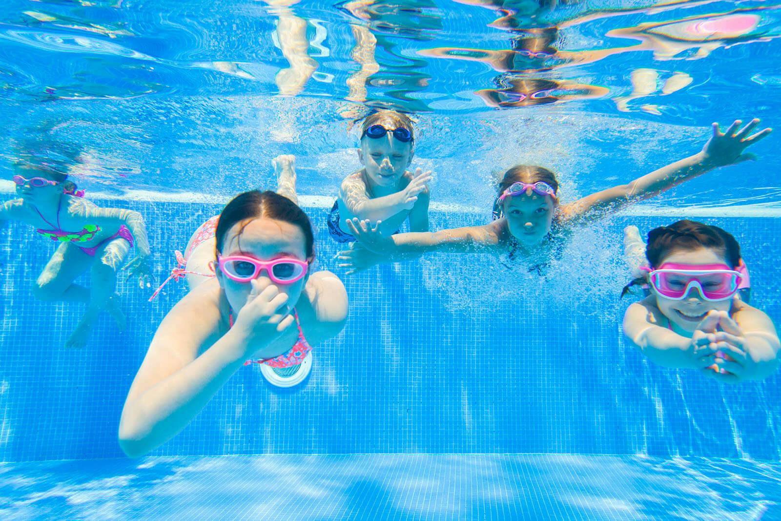Young kids swimming in a pool with their swim gear.