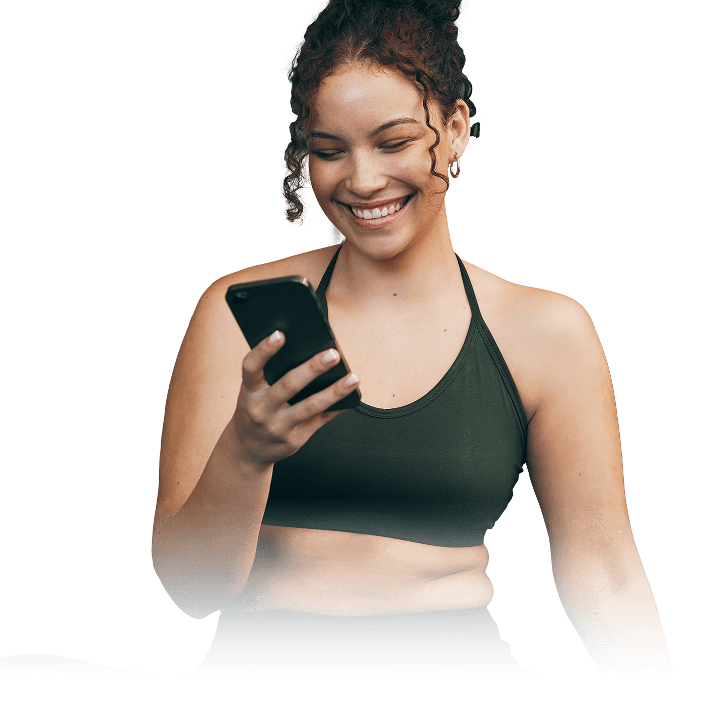 A woman smiling and looking at her phone in her hands.