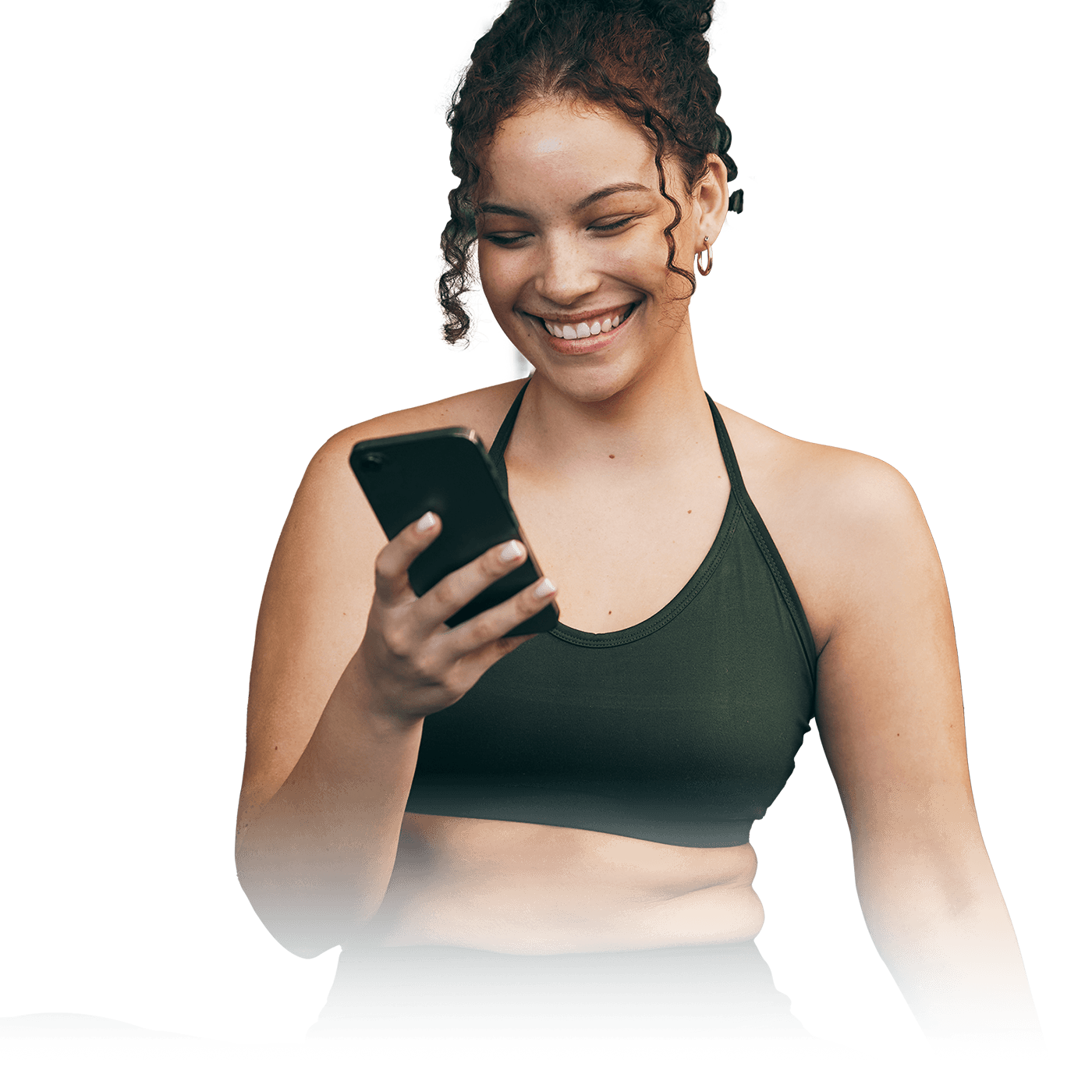 A smiling woman in dark green activewear looks down at a smartphone against a transparent background.